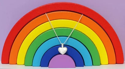 Ascheschmuck-Herzkette „Emmi“ mit Regenbogen-Motiv aus 925er Sterling-Silber vor einer Regenbogendekoration (nicht im Lieferumfang enthalten)