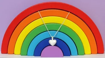 Ascheschmuck-Herzkette „Emmi“ mit Regenbogen-Motiv aus 925er Sterling-Silber vor einer Regenbogendekoration (nicht im Lieferumfang enthalten)